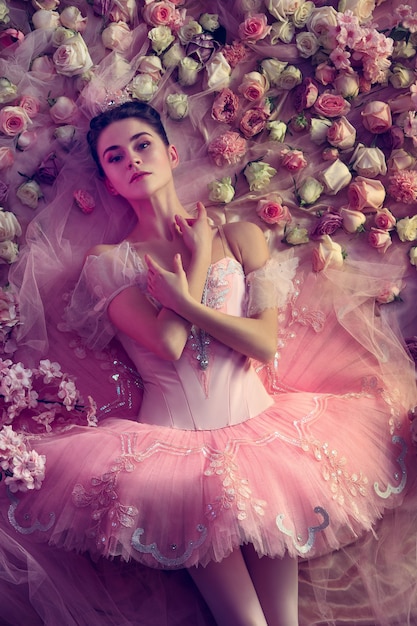 Top view of beautiful young woman in pink ballet tutu surrounded by flowers