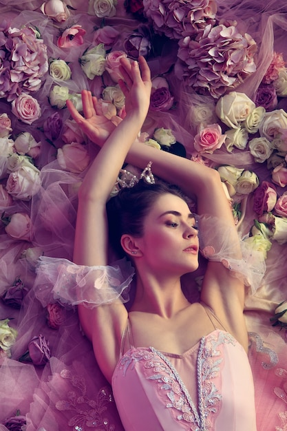 꽃으로 둘러싸인 핑크 발레 투투에서 아름 다운 젊은 여자의 상위 뷰
