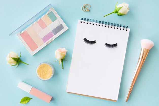 Top view beauty cosmetics with notebook