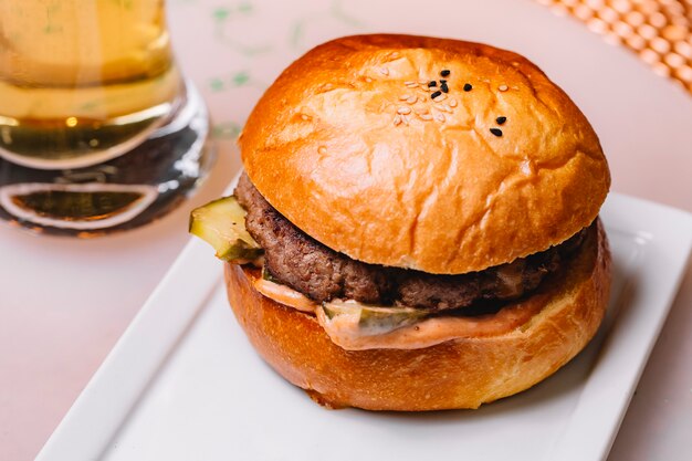 Free photo top view of beef burger with sauce pickled cucumber served at restaurant