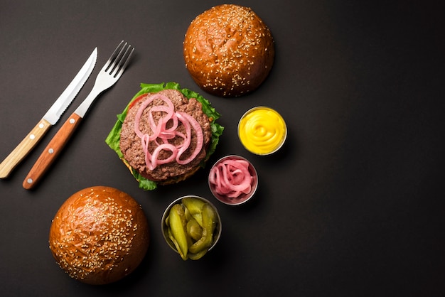 Foto gratuita hamburger di manzo vista dall'alto con salse e posate