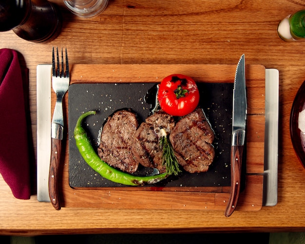 Top view of beef steaks served with grilled tomato and pepper