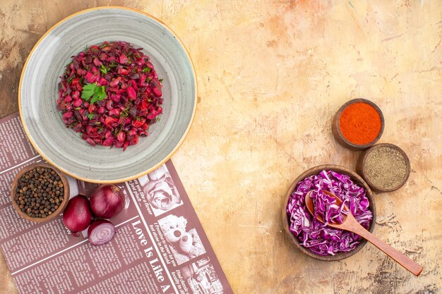 Top view beet salad as a mixture of steamed vegetables such as black pepper red onions ground pepper turmeric and red cabbage in a ceramic gray plate on a light background