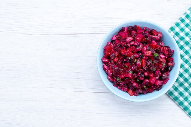 Top view of beet salad sliced with greens inside blue plate on light, salad vegetable vitamine food meal health