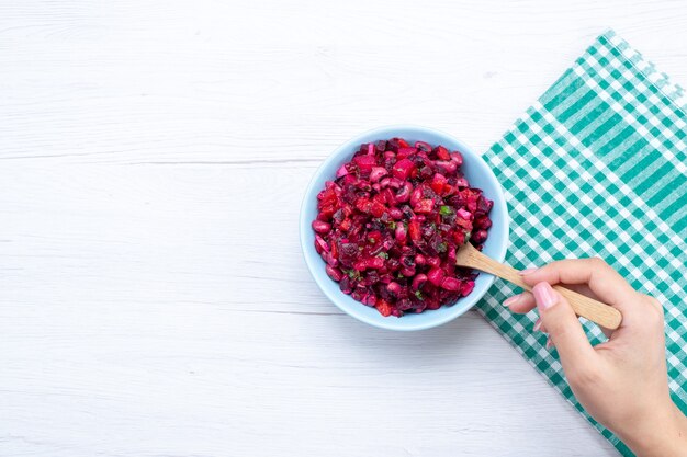 Top view of beet salad sliced with greens inside blue plate on white, salad vegetable vitamine food meal health