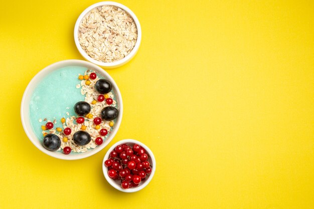 Top view berries bowls of the appetizing red currants and oatmeal and plate of berries