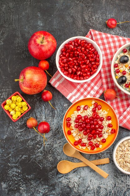 Top view berries bowls of seeds of pomegranate oatmeal berries apples candies on the tablecloth