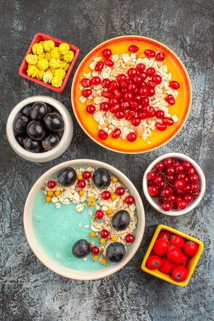 Top view of berries oatmeal pomegranate yellow candies black grapes cherries red currants