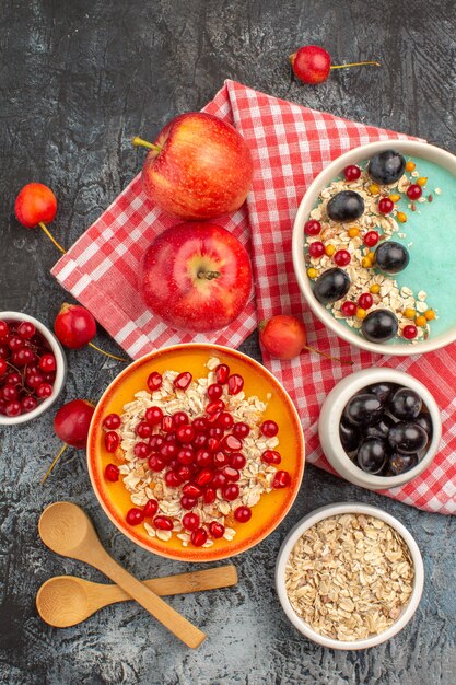 Top view of berries spoons apples colorful berries oatmeal pomegranate
