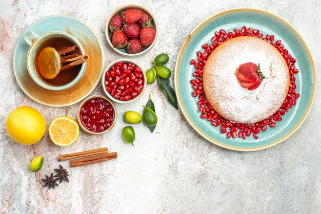 Top view berries and tea a cup of tea jam berries cinnamon sticks the cake with strawberries