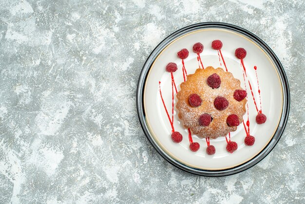 Top view berry cake on white oval plate on grey surface copy space