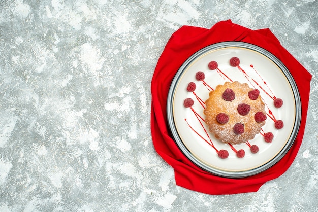 Вид сверху ягодный торт на белой овальной тарелке красный платок на серой поверхности свободное пространство