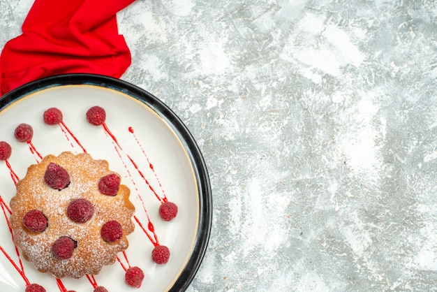 Free photo top view berry cake on white oval plate red shawl on grey surface with copy space