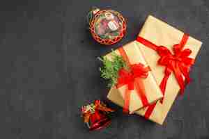 無料写真 暗い表面に赤いリボンのクリスマスツリーのおもちゃで結ばれた茶色の紙の上面図大小のクリスマスプレゼント