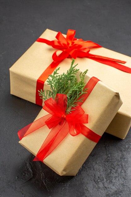 어두운 표면에 빨간 리본으로 묶인 갈색 종이의 크고 작은 크리스마스 선물