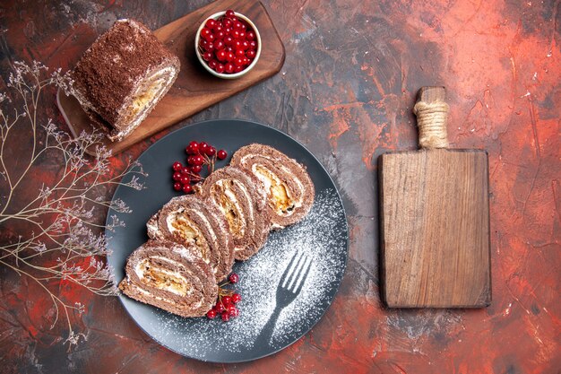 Top view of biscuit rolls slices with fruits on dark surface