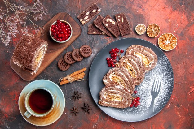 Top view of biscuit rolls with cup of tea on dark surface