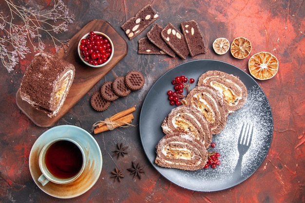 Top view of biscuit rolls with cup of tea on dark surface