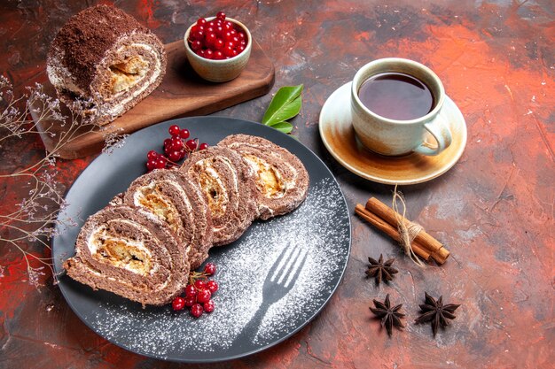 Top view of biscuit rolls with cup of tea on dark surface