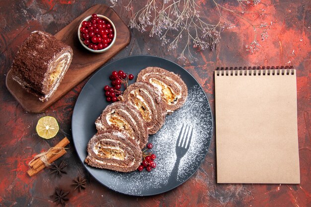 Top view of biscuit rolls with red fruits on dark surface