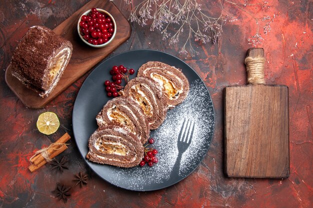 Top view of biscuit rolls with red fruits on dark surface