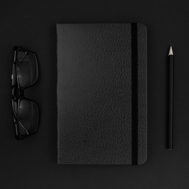 Top view of black agenda and glasses