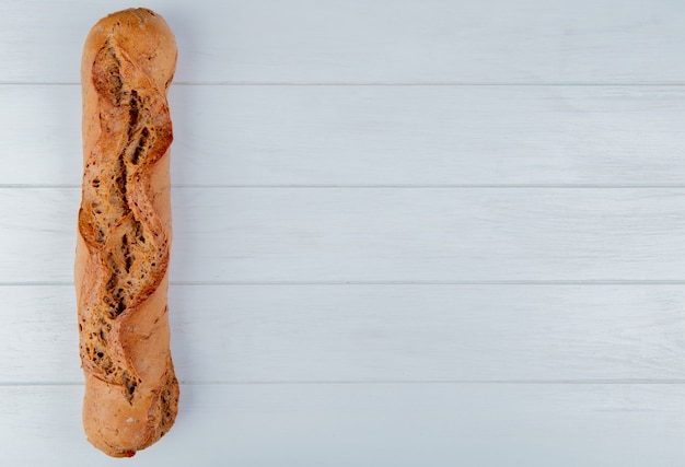 Top view of black baguette on left side and wooden background with copy space