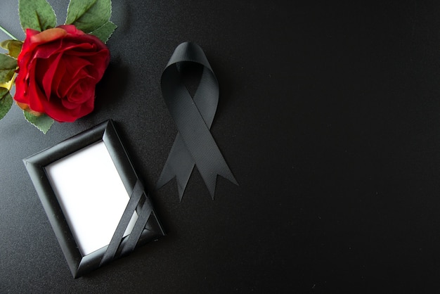 Top view of black bow with red flower on a dark wall