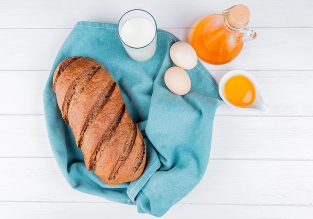 Top view of black bread and milk eggs on blue cloth with melted butter on wooden table