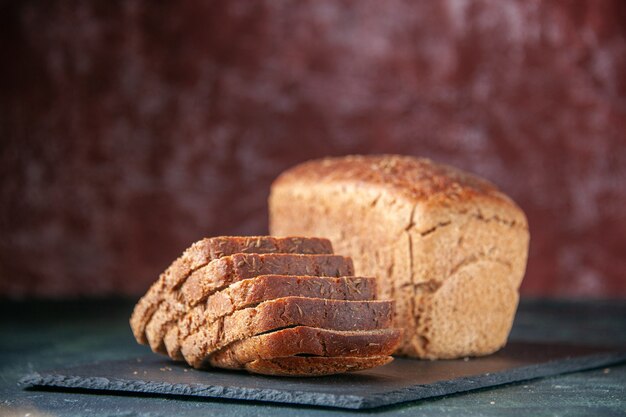 Top view of black bread slices on black wooden tray on mixed colors distressed background