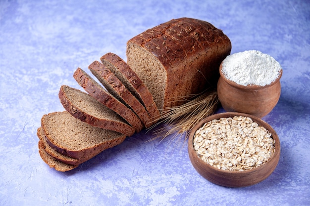 Top view of black bread slices flour oatmeal on light ice blue pattern background with free space