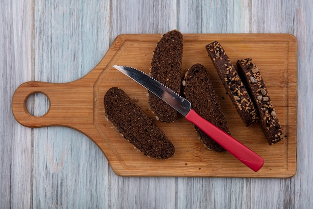 Top view black bread with knife on cutting board  on gray background