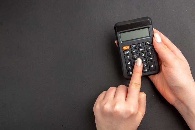 Вид сверху черный калькулятор в женских руках на черном столе свободное пространство