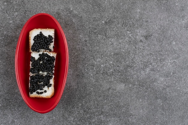 Free photo top view of black caviar with bread in red bowl