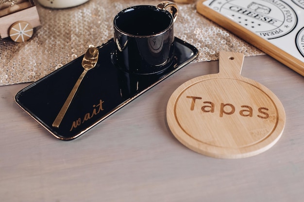 Top view of black coffee mug near wooden cutting board for cheese. Copy space