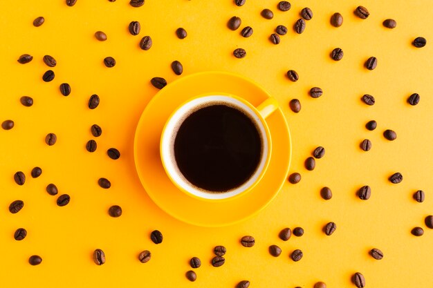 Top view black coffee surrounded by beans