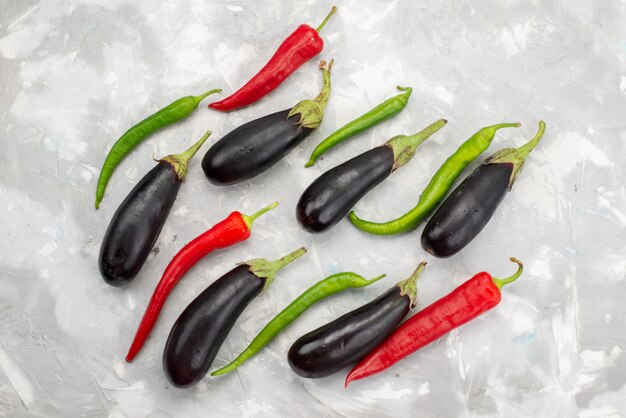 Top view black eggplants with peppers on the bright backgorund vegetable spice food raw color