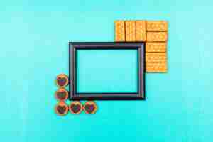 Foto gratuita cornice nera vista dall'alto con biscotti e copia spazio sulla superficie blu