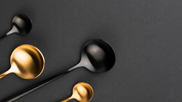 Top view of black and golden spoons with copy space