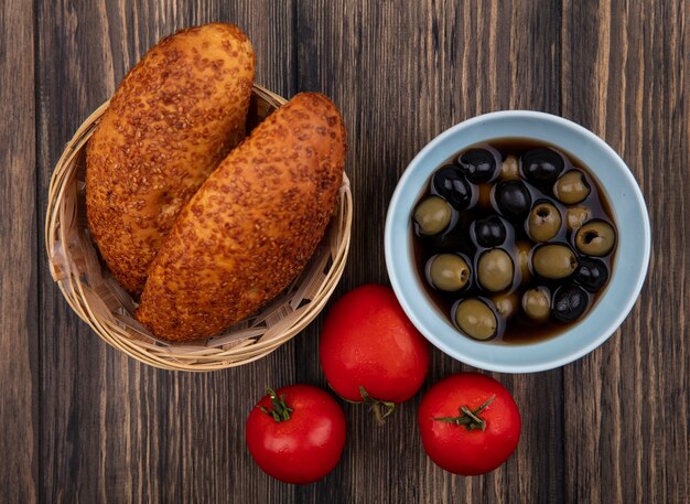 Foto gratuita vista dall'alto di olive nere e verdi su una ciotola blu con polpette su un secchio con pomodori isolato su uno sfondo di legno