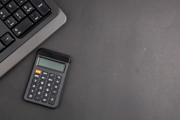 Top view black office stuffs keyboard calculator on dark table copy space