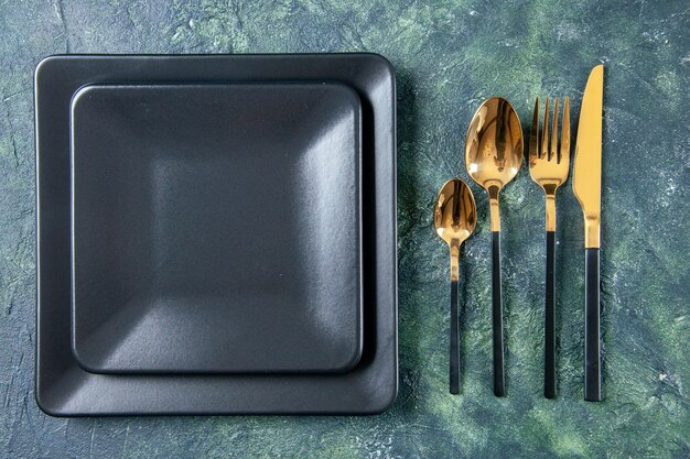 вид сверху черные тарелки с золотой вилкой, ложки и нож на темном фоне цветная еда столовые приборы ресторанное обслуживание ужин кухня кафе