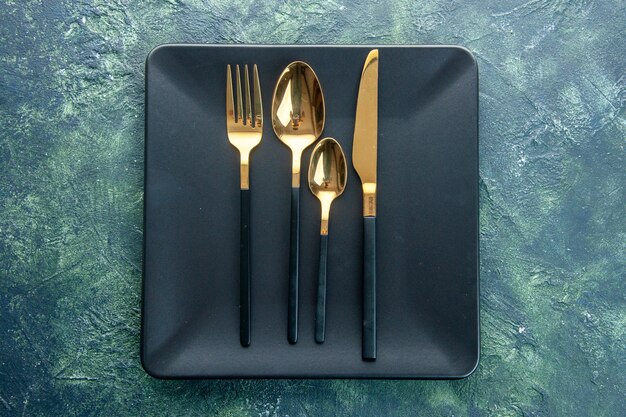 вид сверху черные тарелки с золотыми ложками нож и вилка на темном фоне цвет еда ужин кухня ресторан столовые приборы