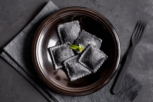 Top view black ravioli on plate with fork