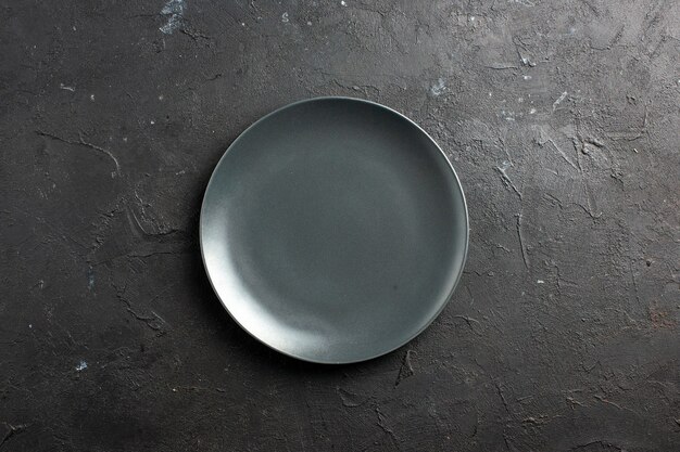 Вид сверху черная салатная тарелка на черной поверхности свободного пространства