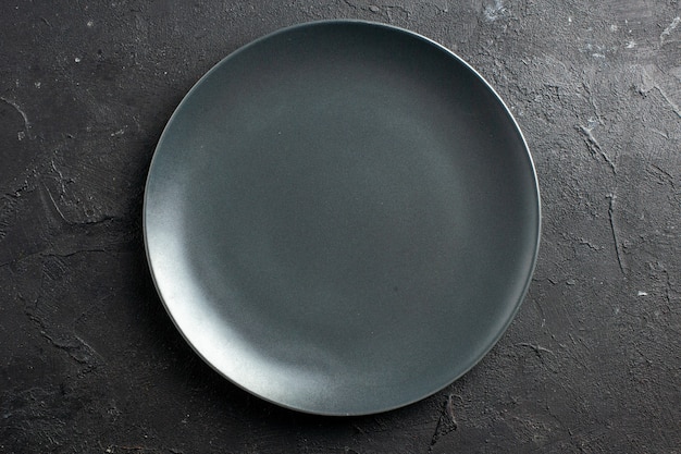 Вид сверху черная салатная тарелка на черной поверхности