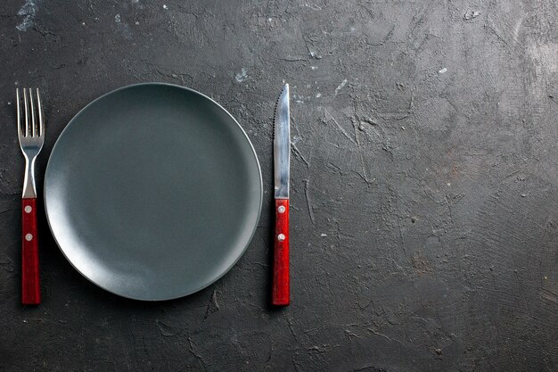 Top view black salad plate fork and knife on black surface copy space