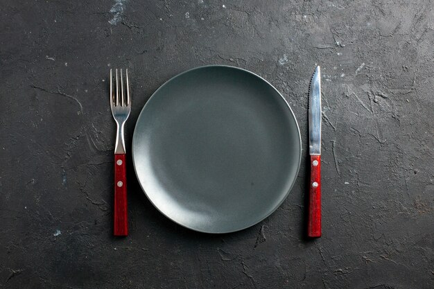 Top view black salad plate fork and knife on black surface