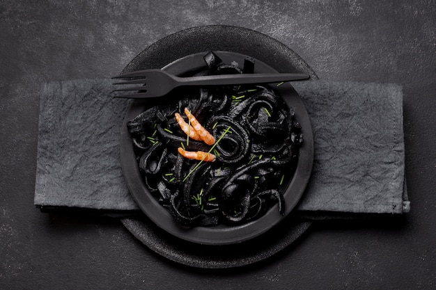 Foto gratuita vista dall'alto di gamberi neri con forchetta e tovagliolo