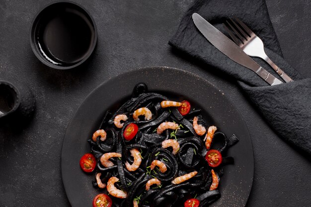 Top view black shrimp pasta with soy sauce and cutlery